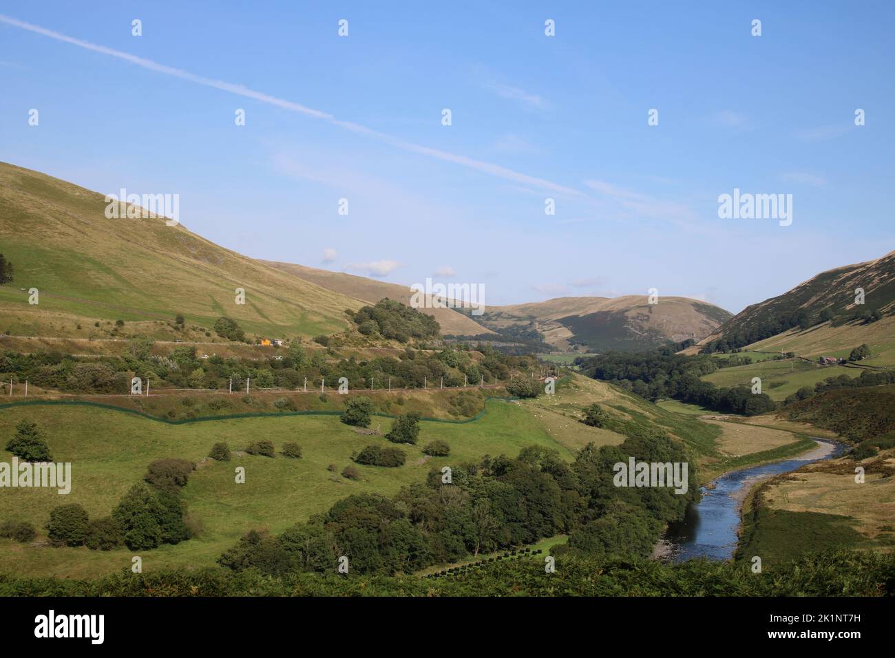View up Lune gorge in Cumbria, River Lune in bottom of valley, M6 motorway and West Coast Main Line railway on hillside. Sunny September day in 2022. Stock Photo
