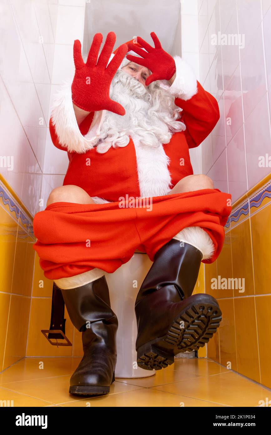 Santa Claus is surprised from the paparazzi photographer when sitting on the toilet Stock Photo
