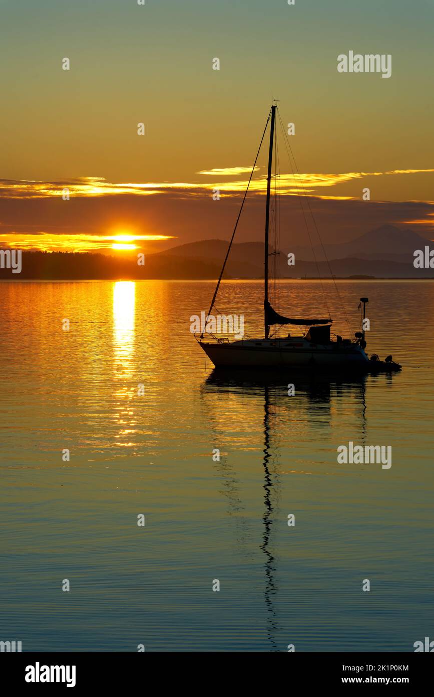 Pacific Northwest Sunrise Sailboat at Anchor. A sailboat anchored at sunrise in the Pacific Northwest. Stock Photo