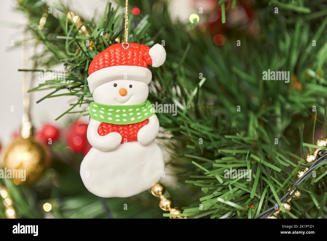 Close-up view of a decorated Christmas tree, friendly snowman hanging on a branch. Composition with copy space. Stock Photo
