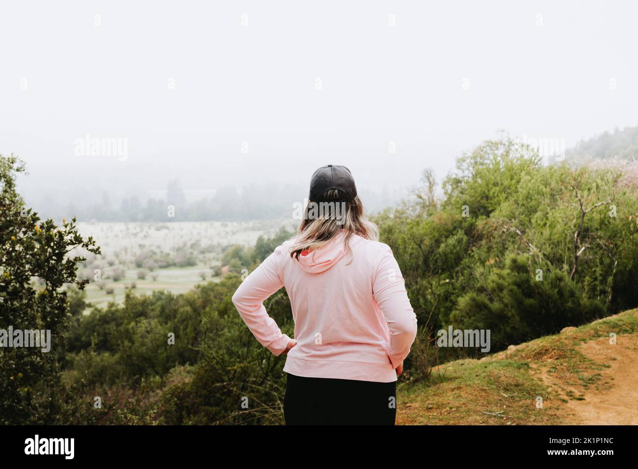 Unrecognizable latin plus size woman, climbing a hill and hiking in a beautiful landscape. Stock Photo