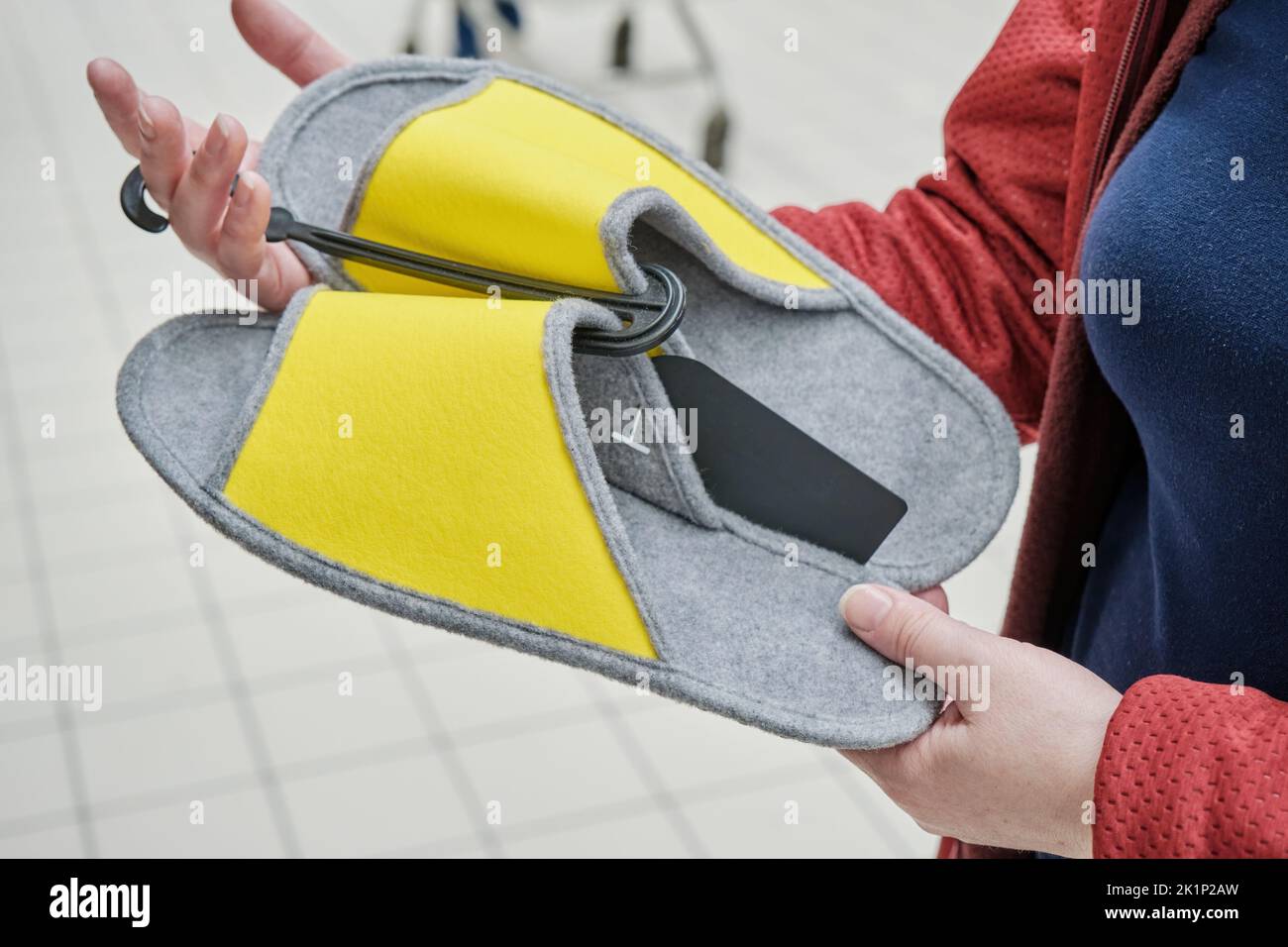 Woman chooses soft yellow felt slippers in store to buy. Hands close up Stock Photo