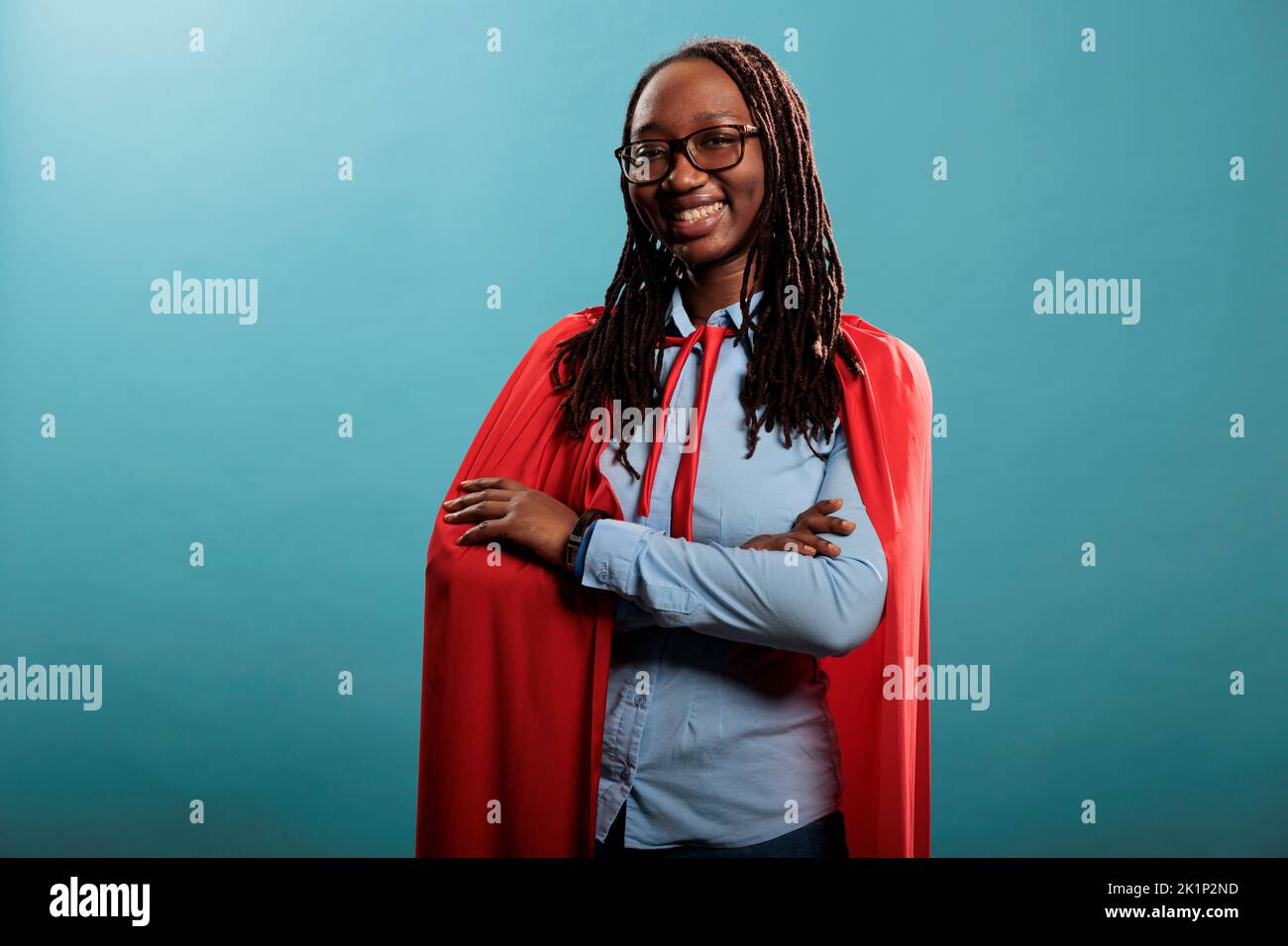 Portrait of happy brave woman with superpowers wearing red hero cape ...