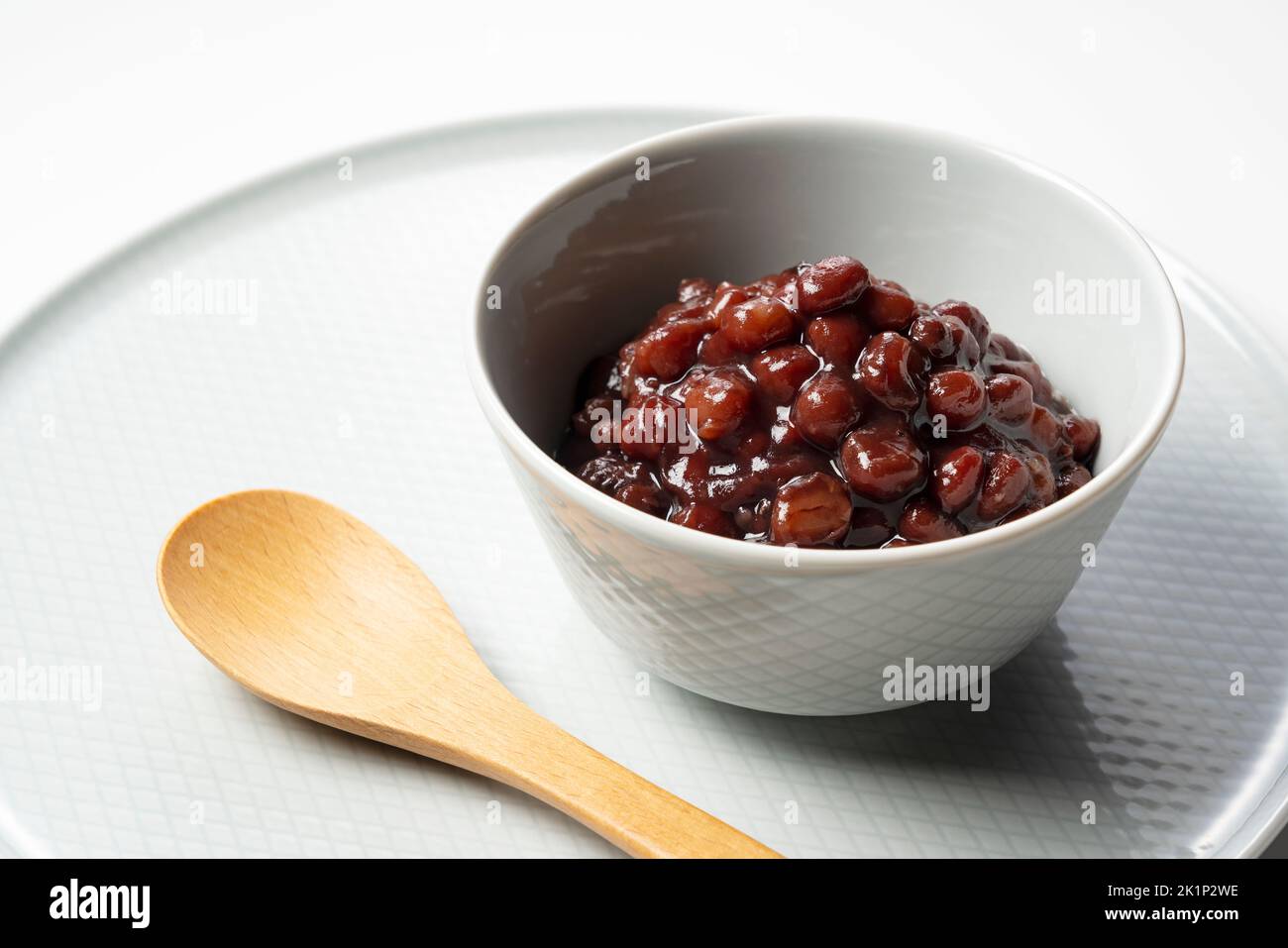 Boiled azuki beans in a small bowl placed against a white background. Stock Photo