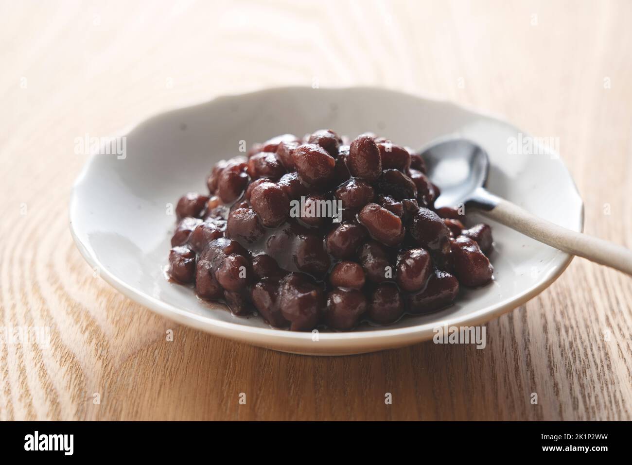 Boiled azuki beans in a dish placed on a wooden background. Stock Photo