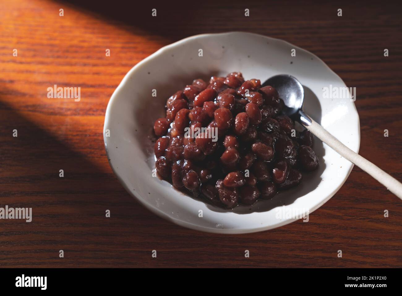 Boiled azuki beans in a dish placed on a wooden background. Stock Photo