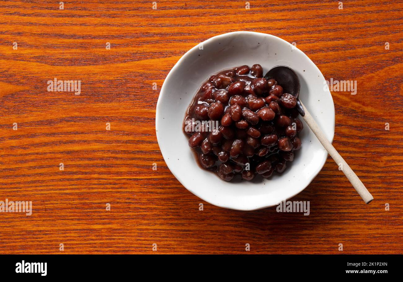 Boiled azuki beans in a dish placed on a wooden background. View from above. Stock Photo