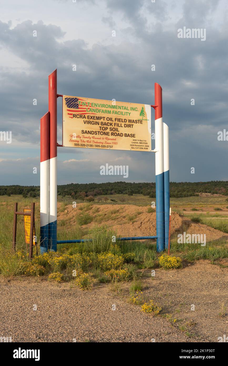 A sign for TNTEnvironmental Inc Landfill Facility, RCRA Exempt Oil Field Waste with red, white and blue fence posts, Northern New Mexico. Stock Photo