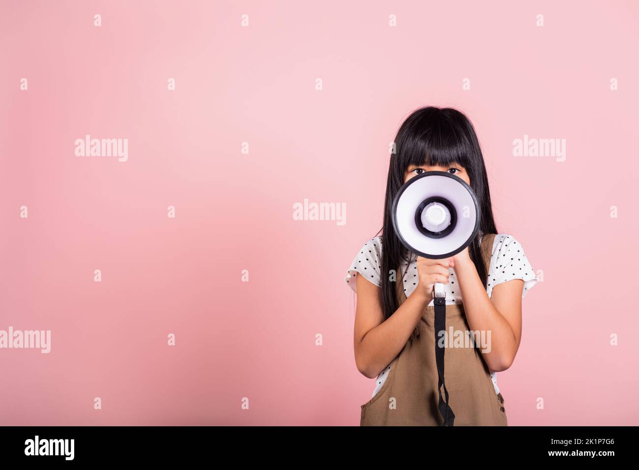 Asian little kid 10 years old shouting by megaphone at studio shot isolated on pink background, Happy child girl lifestyle she screeching through in m Stock Photo