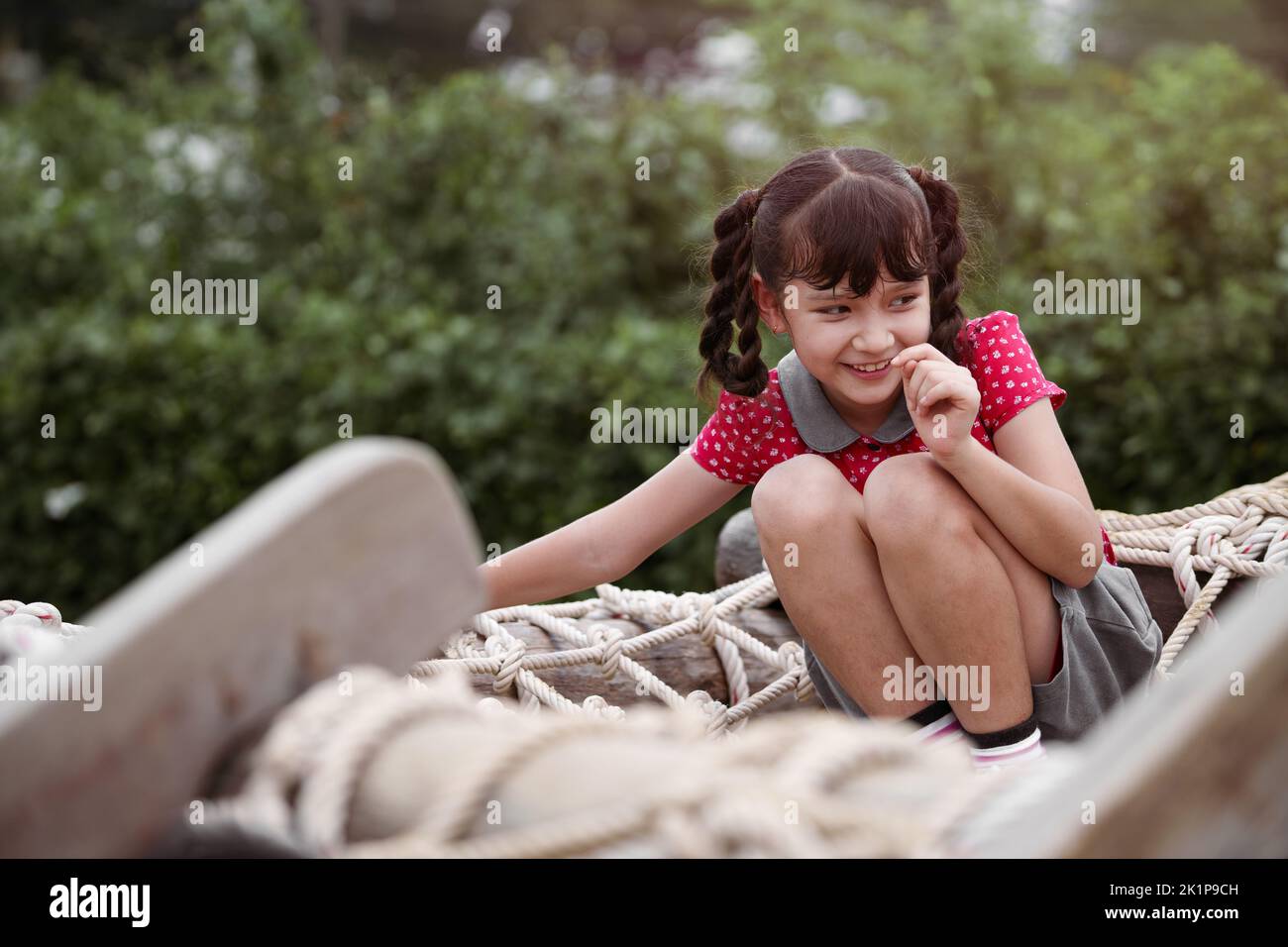 Happy girl playing on a tightrope in a playground. Stock Photo