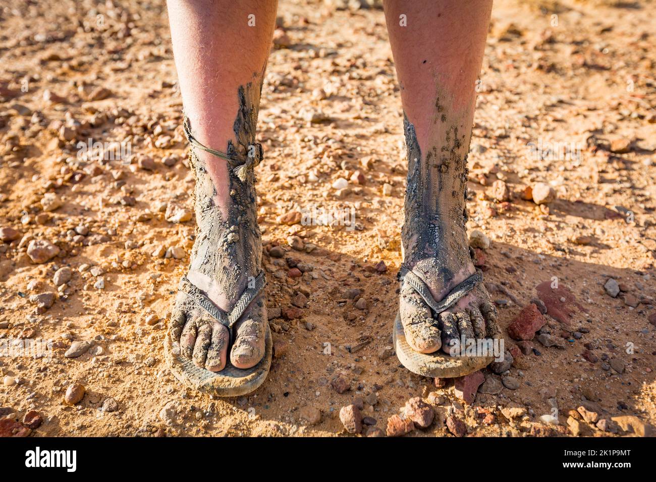 Two muddy feet of a girl wearing thongs after walking through the mud