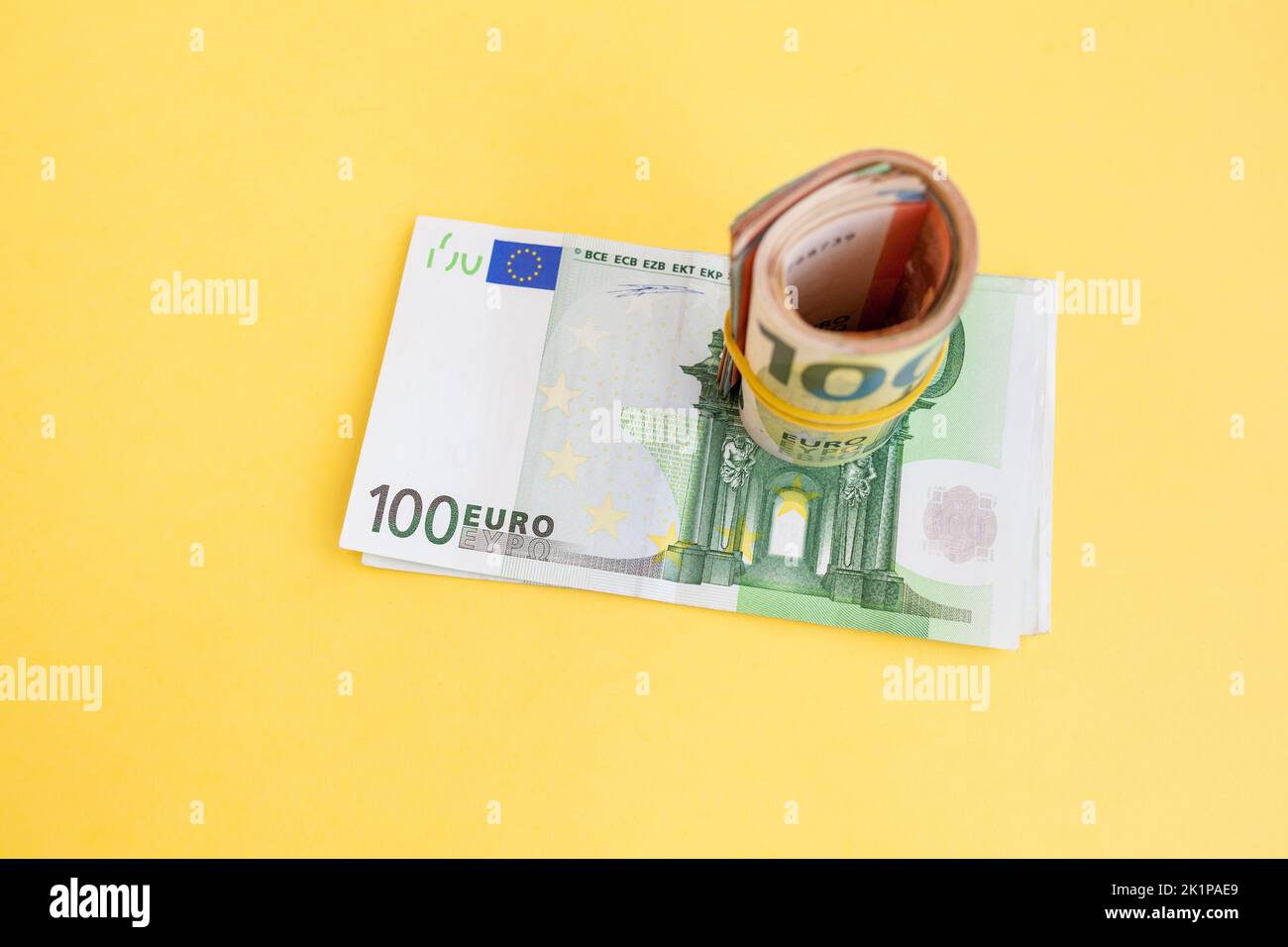 Money roll euro banknotes with yellow rubber band on yellow background Stock Photo