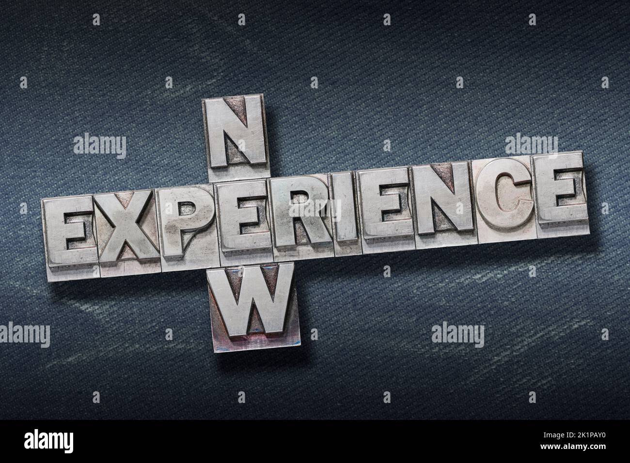 new experience crossed phrase made from metallic letterpress on dark jeans background Stock Photo