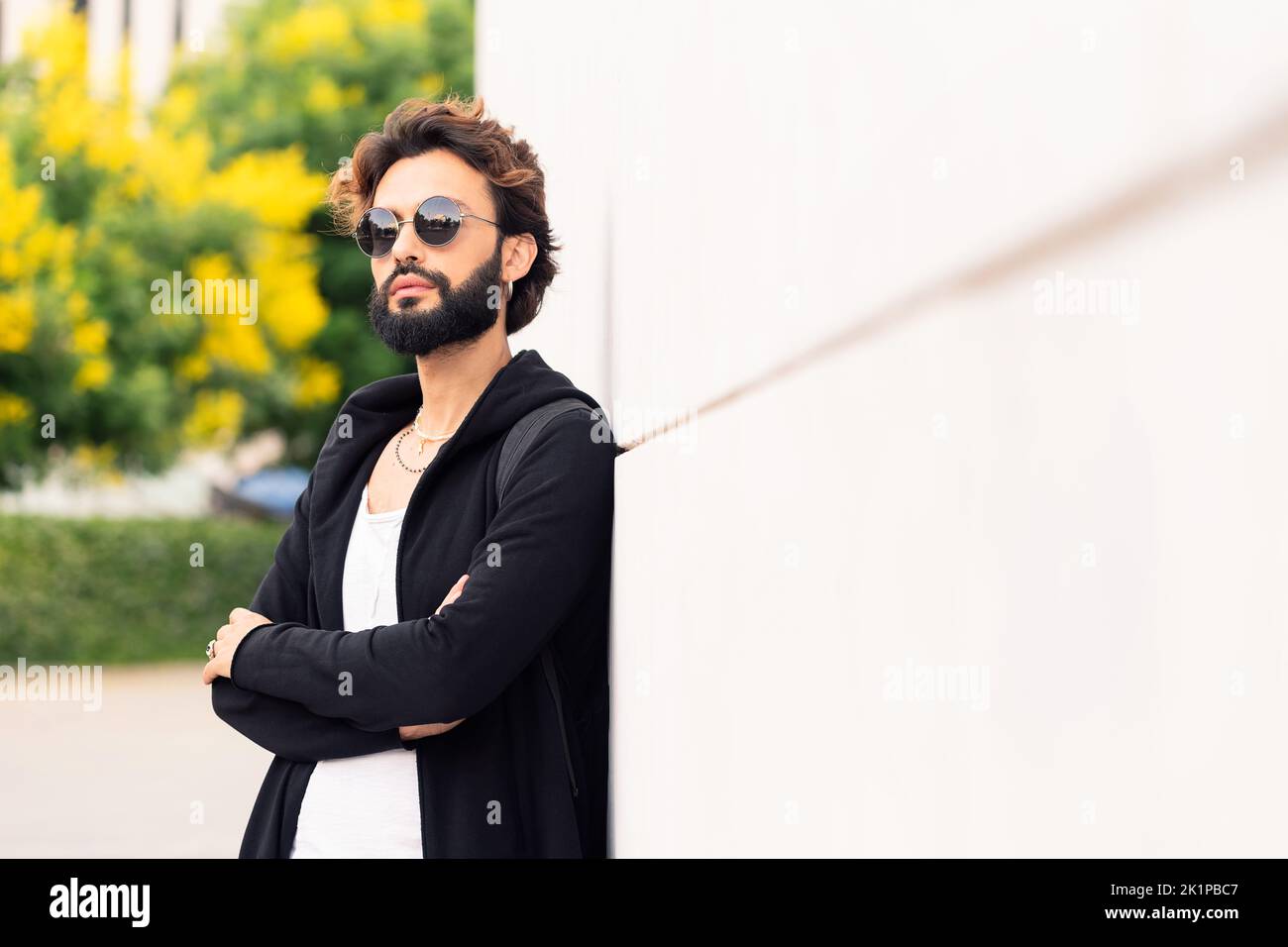 young man with sunglasses leaning in a white wall Stock Photo