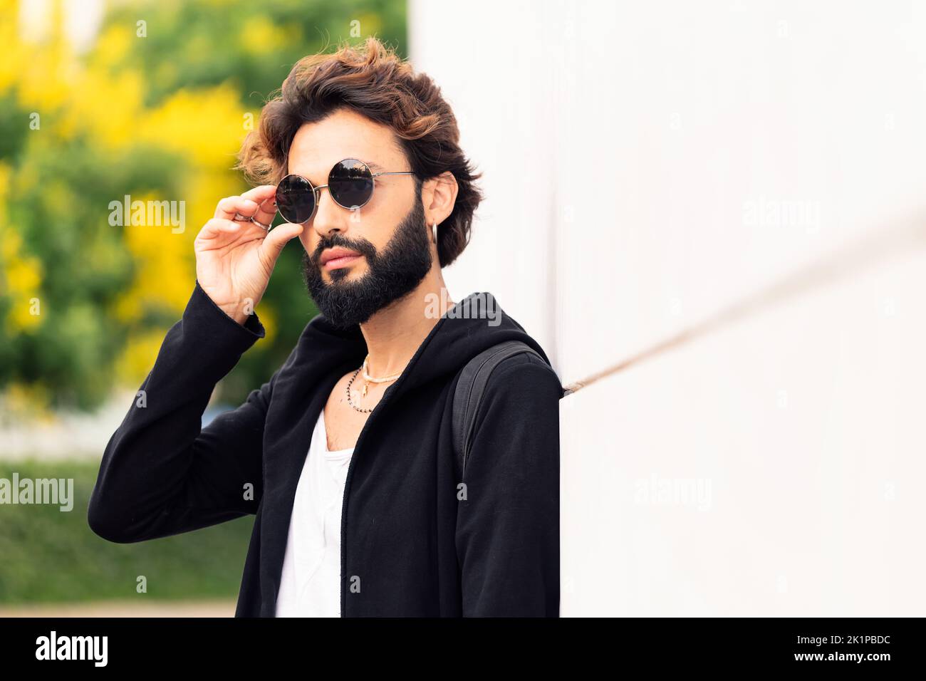 man putting on sunglasses leaning in a white wall Stock Photo - Alamy