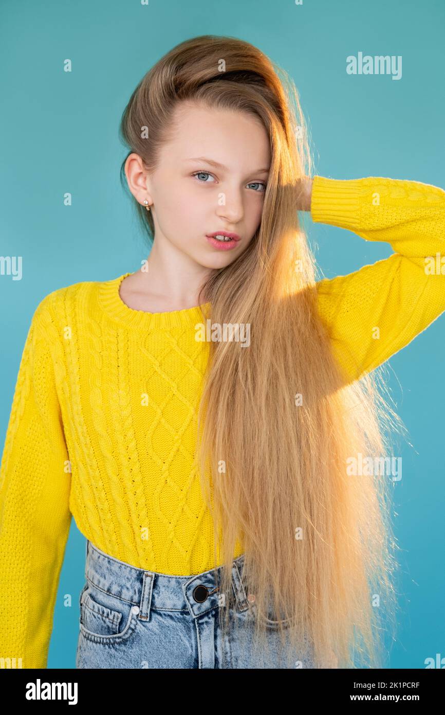 Child fashion. Casual style. Fall collection. Portrait of pretty elegant young model girl with long fair hair in yellow sweater jeans posing isolated Stock Photo