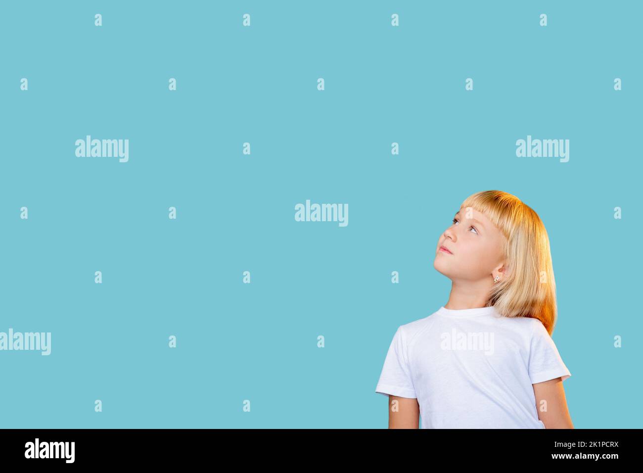 Curious kid. Promotional background. Attractive opportunity. Hard choice. Portrait of puzzled pensive blonde little girl looking up reading considerin Stock Photo