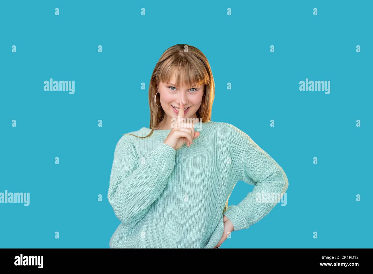 Female secret. Hush gesture. Special offer. Surprise opportunity. Portrait of amused playful woman in sweater showing shhh with finger at mouth isolat Stock Photo