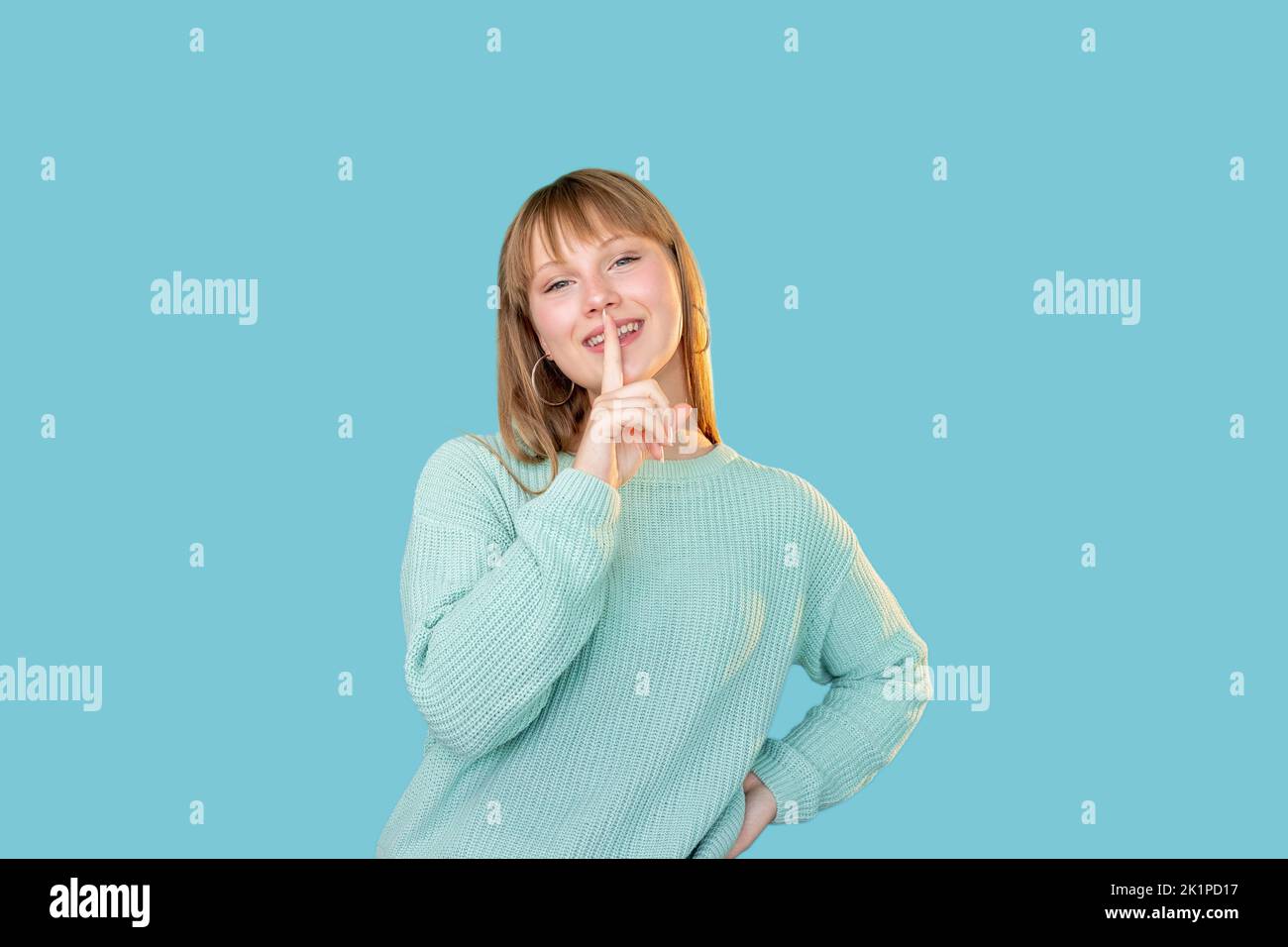 Female gossip. Shush gesture. Dont speak. Special surprise. Portrait of happy enthusiastic fun woman in sweater showing shhh with finger at mouth isol Stock Photo