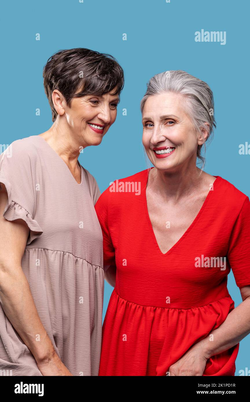 Pretty mature ladies in dresses looking happy Stock Photo