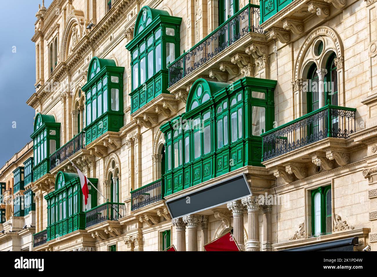 Fragment of the building's facade with traditional wooden ornate balconies painted in green in Valletta, Malta. Stock Photo