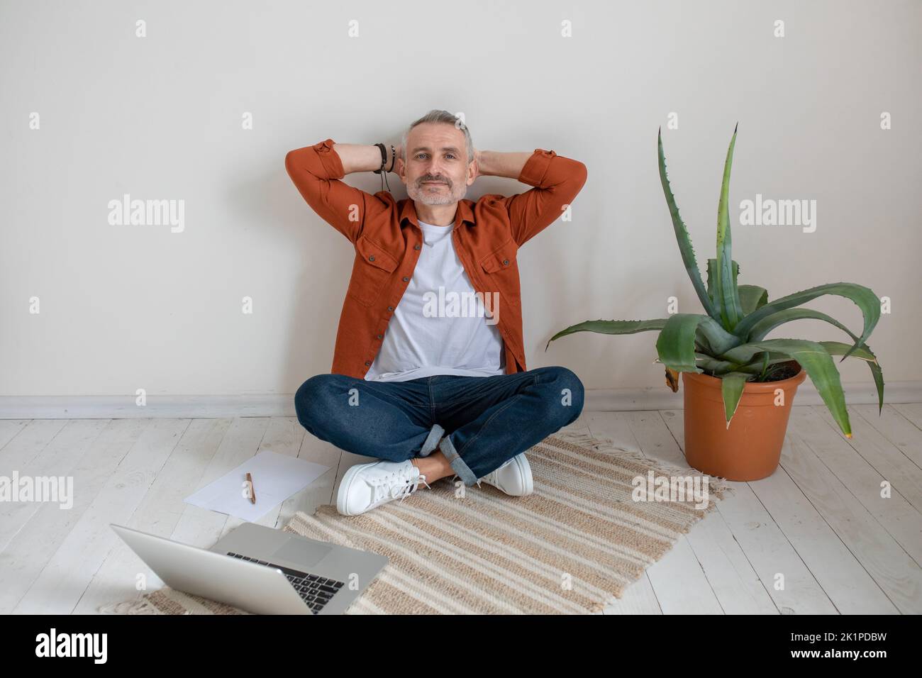A man sitting on the floor with his legs crossed and resting from work Stock Photo