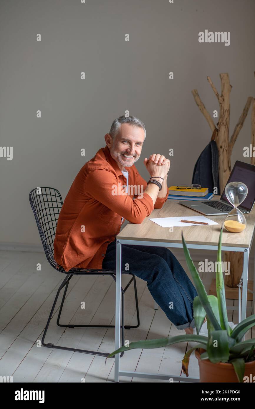 A man sitting at the table in the offcie and looking contented Stock Photo