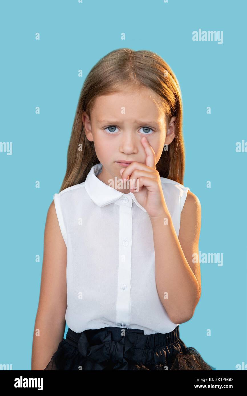 Offended kid. Unfair punishment. Sorrow disappointment. Portrait of unhappy crying sweet little girl in elegant outfit wiping tear with finger isolate Stock Photo