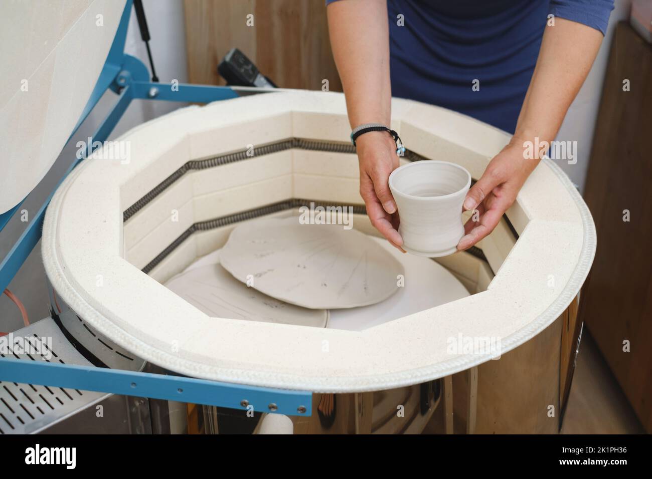 close-up of hands putting vase into the kiln, oven for roasting of unbaked clay handmade products, Unfinished ceramics and utensil. Modern pottery Stock Photo