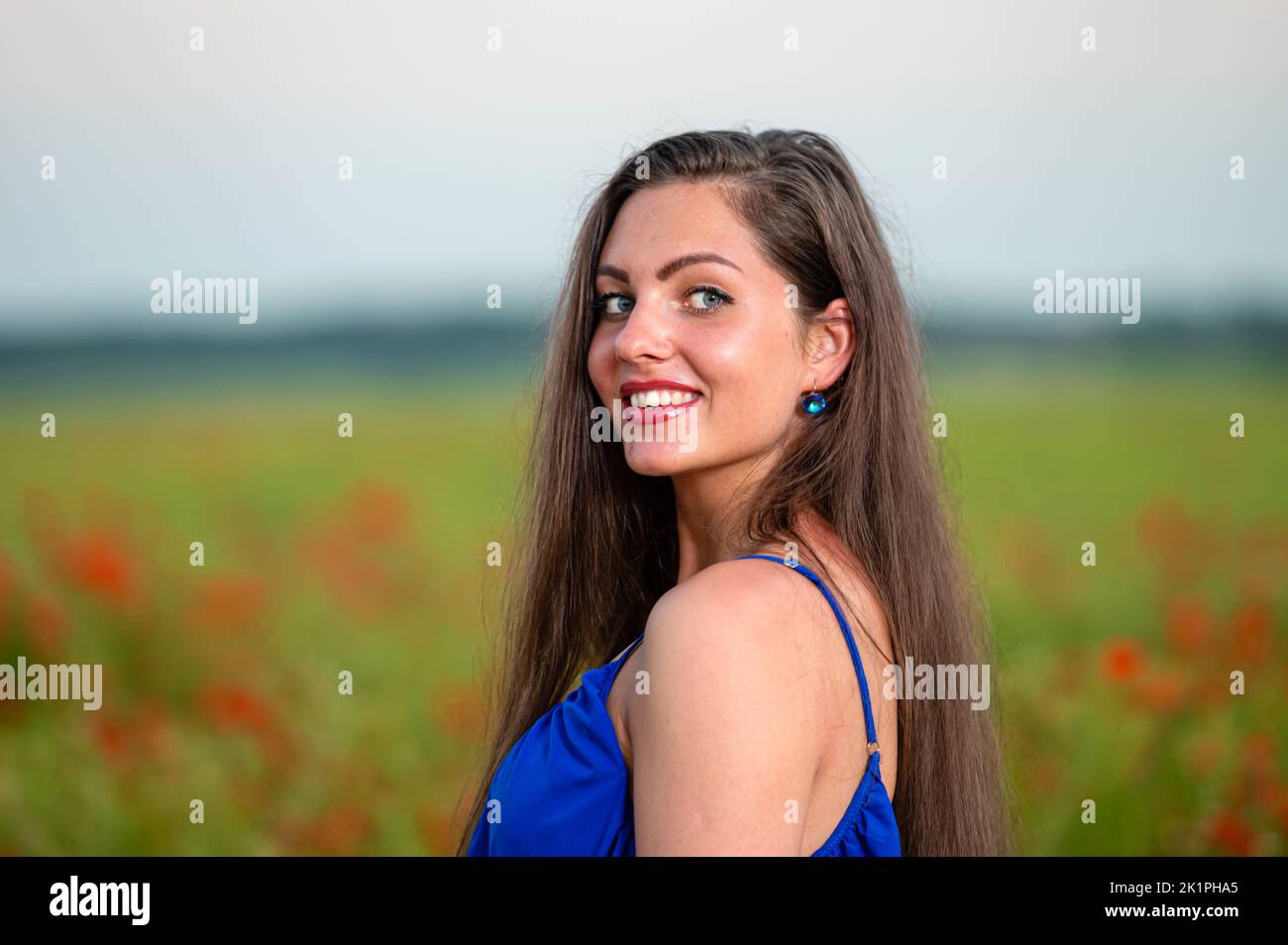 portrait of elegant young woman with long hair in poppy field in ...