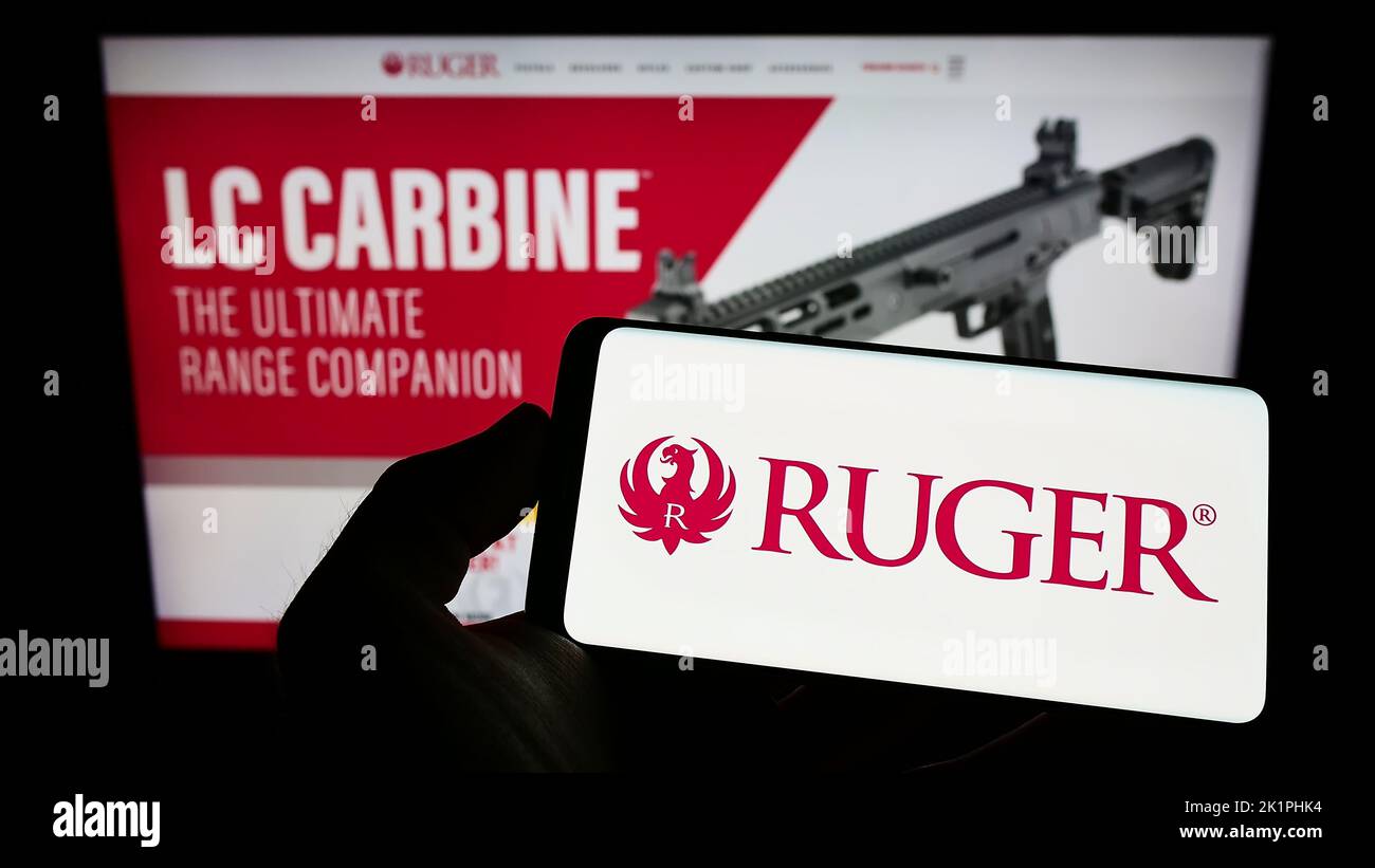 Person holding smartphone with logo of US company Sturm, Ruger and Company Inc. on screen in front of website. Focus on phone display. Stock Photo