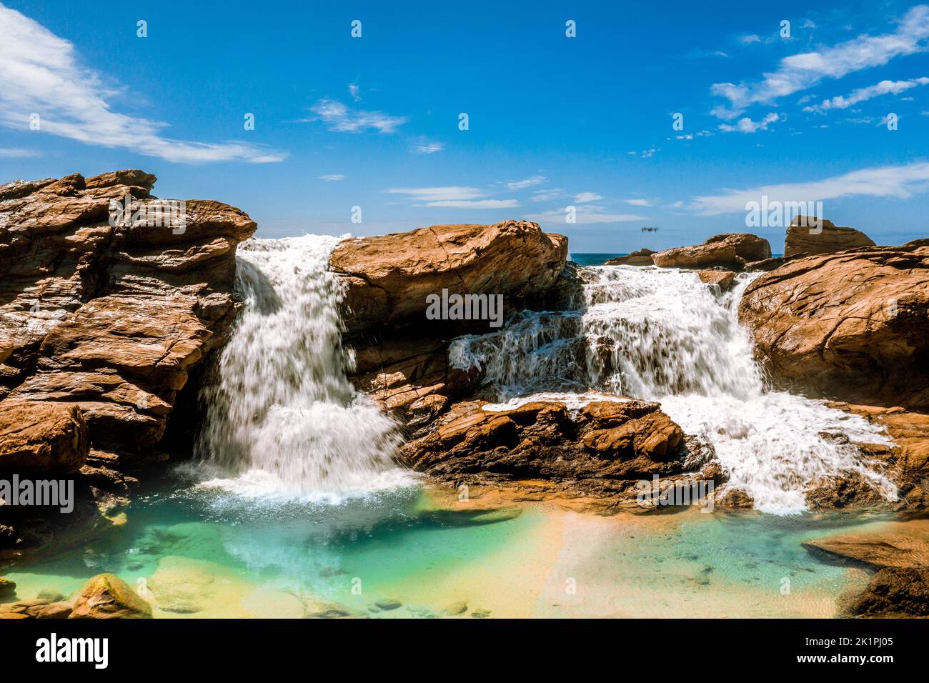 Water tumbles over rocks and into an ocean rockpool Stock Photo