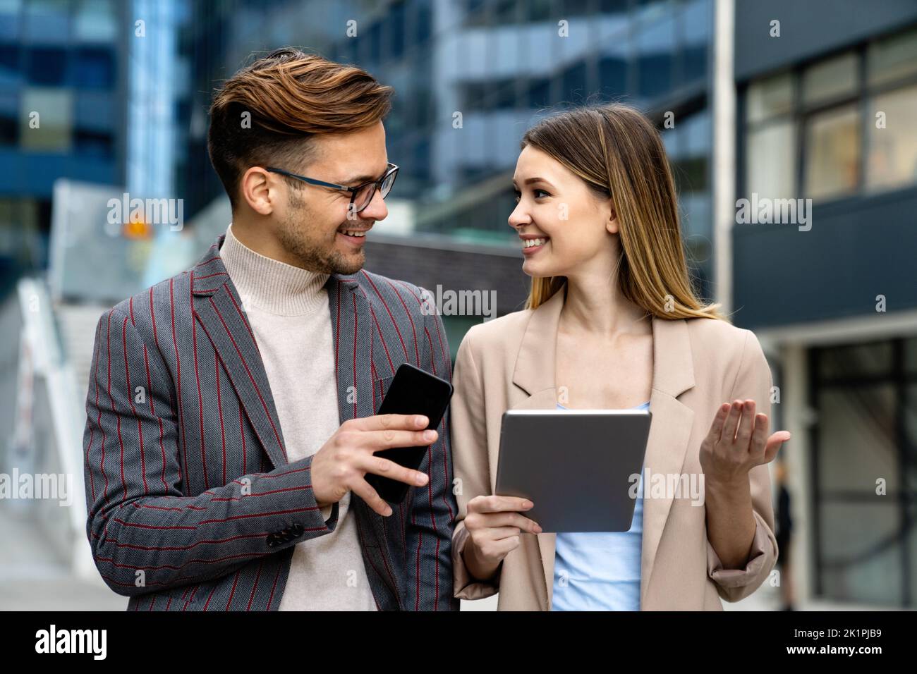 Successful young business people talking, working together in front of modern business building Stock Photo