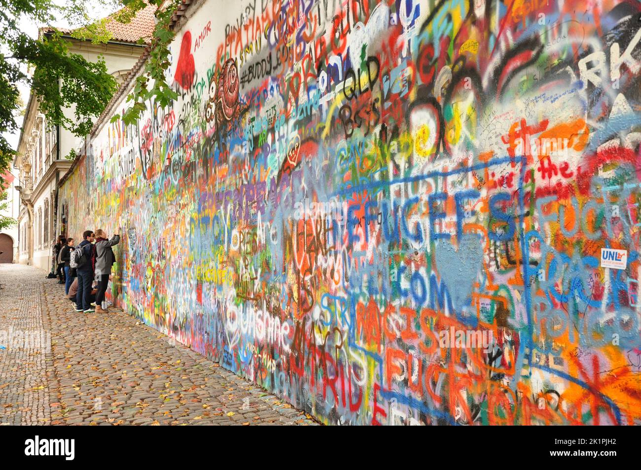 A group of young people paint a graffiti on the John Lennon Wall in ...