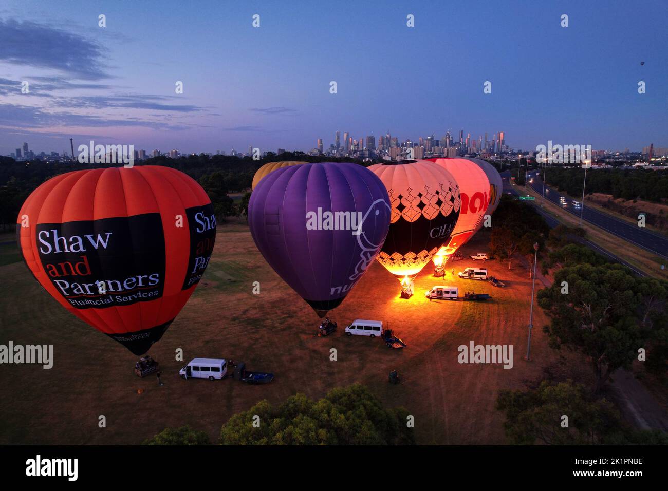 A group of colorful hot air balloons filling up ready to take off in Melbourne at sunset Stock Photo