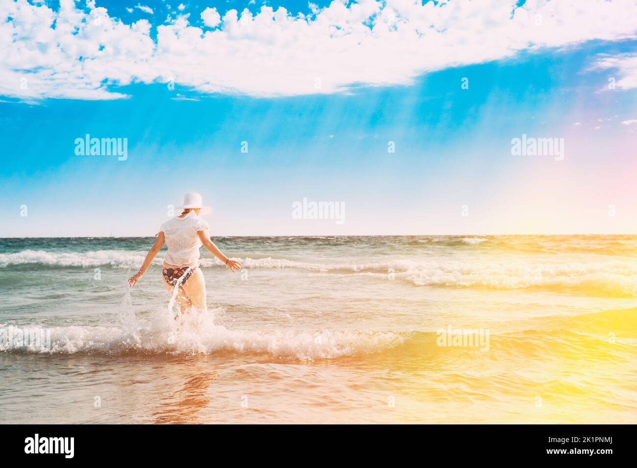 Active Caucasian Young Woman Goes Towards In Sea Ocean. Happy Seaside Vacation. Beach Relaxing Vacation Concept. Happy Beautiful Girl On Beach Stock Photo