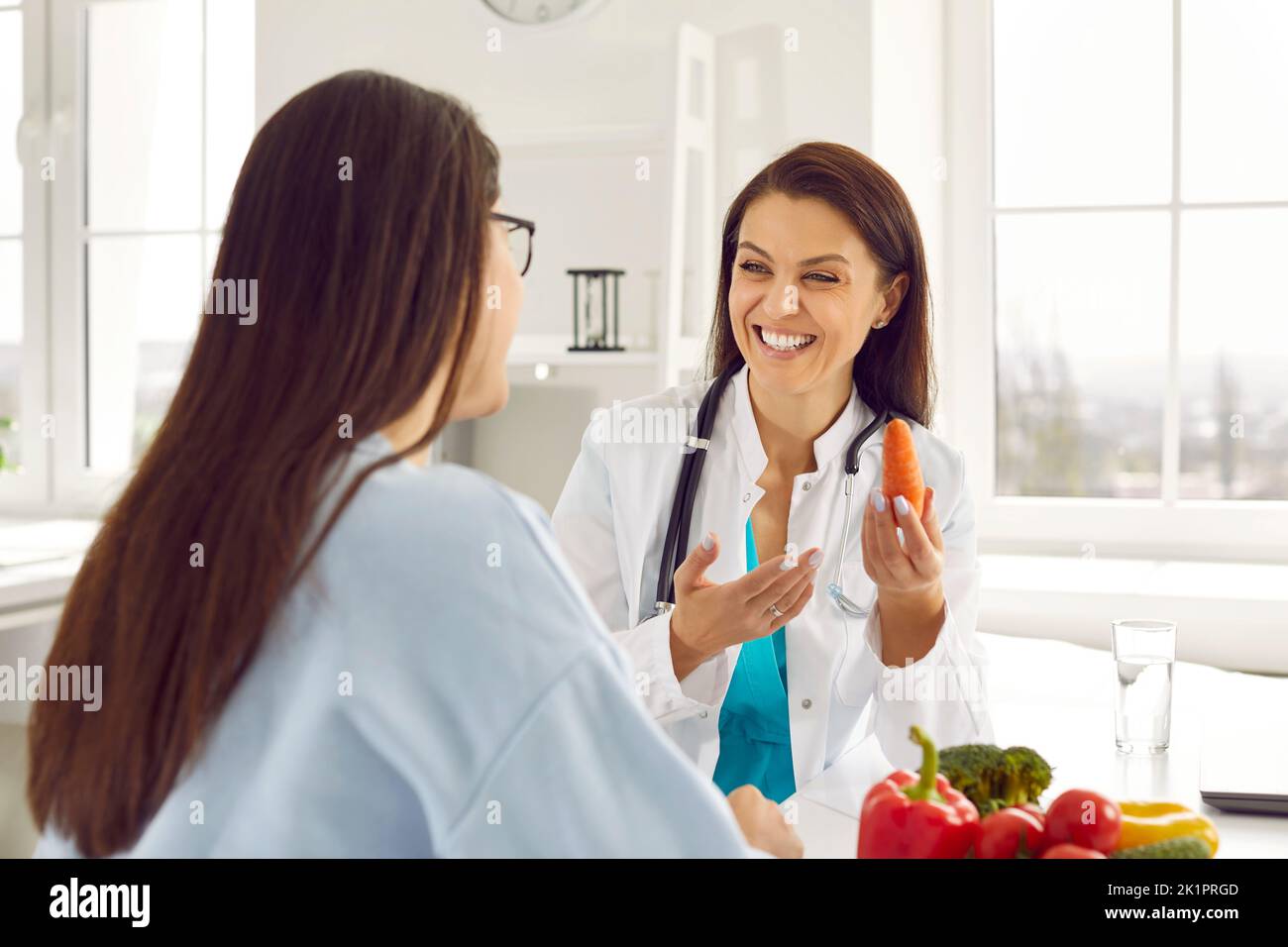 Happy doctor, dietitian or nutritionist giving nutrition consultation to young woman Stock Photo
