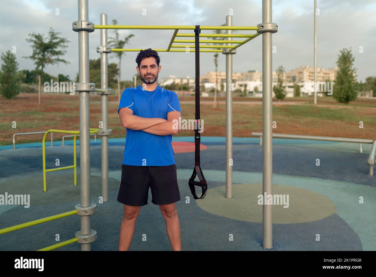 Portrait of confident young man doing fitness exercises on a special hanging device. Fitness male guy doing exercising with suspension trainer slingin Stock Photo