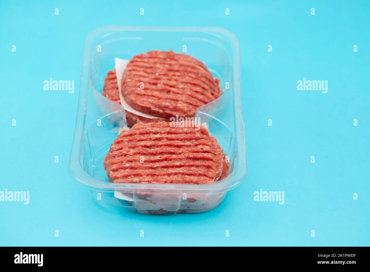 fresh raw minced meat in plastic box on blue paper Stock Photo