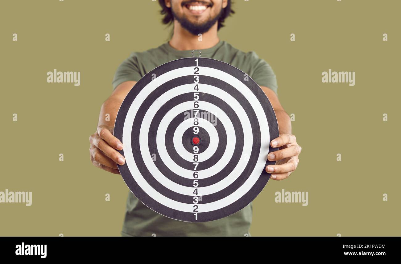Purposeful man with smile holds out dartboard to camera symbolizing desire to achieve target Stock Photo
