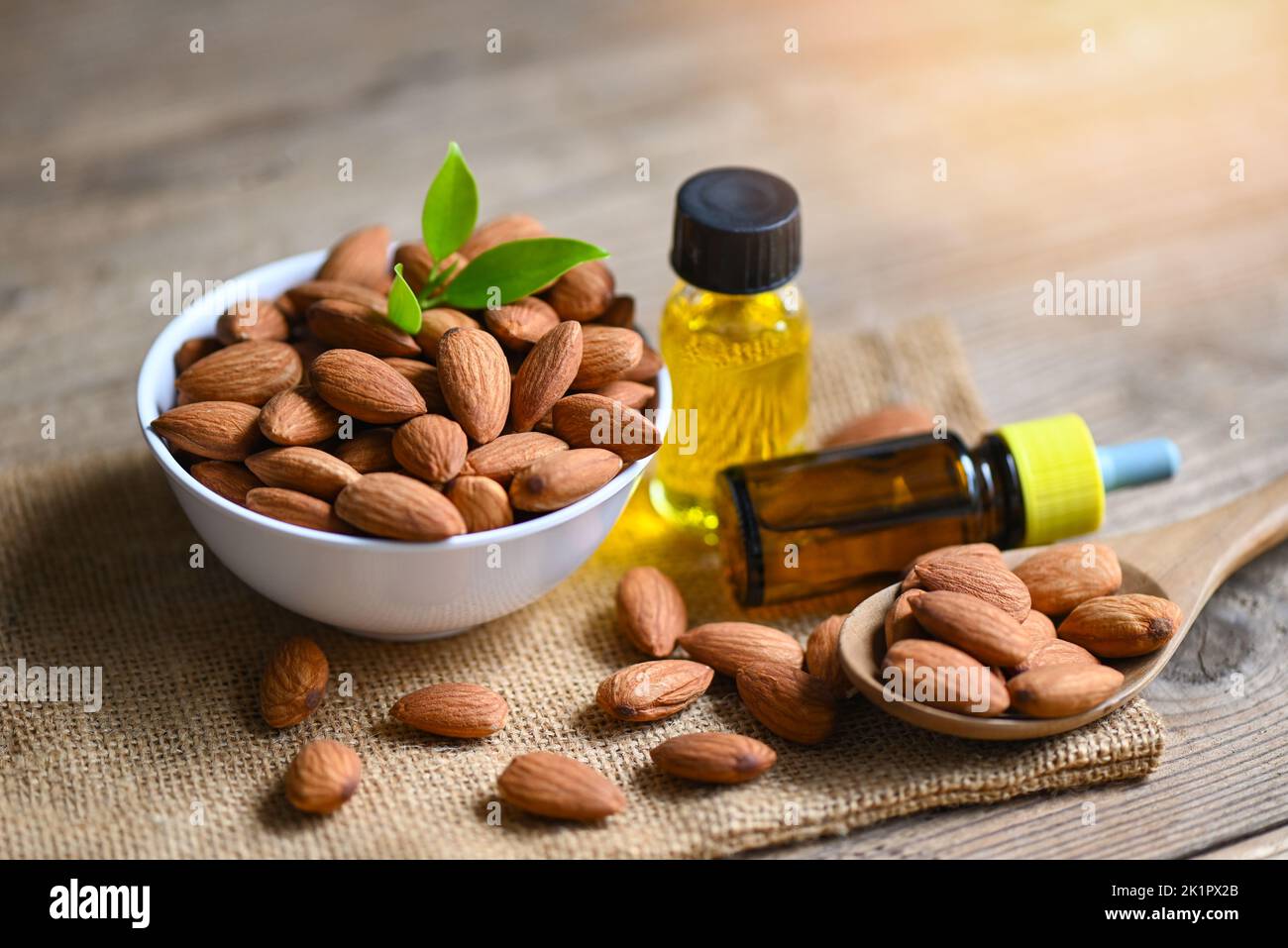 Almond oil and Almonds nuts on bowl, Delicious sweet almonds oil in glass bottle, roasted almond nut for healthy food and snack organic vegetable oils Stock Photo