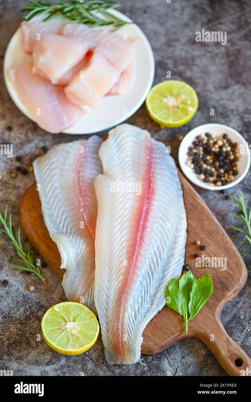 fish fillet on wooden board with ingredients for cooking, meat dolly fish tilapia striped catfish, fresh raw pangasius fish fillet with herb and spice Stock Photo