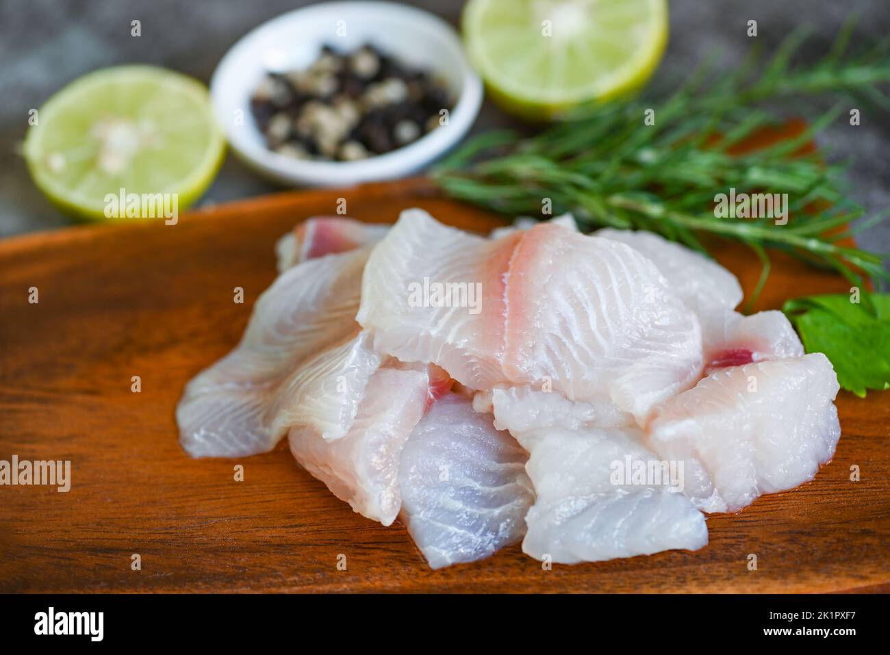 fresh raw pangasius fish fillet with, meat dolly fish tilapia striped catfish, fish fillet on wooden board with ingredients celery for cooking Stock Photo