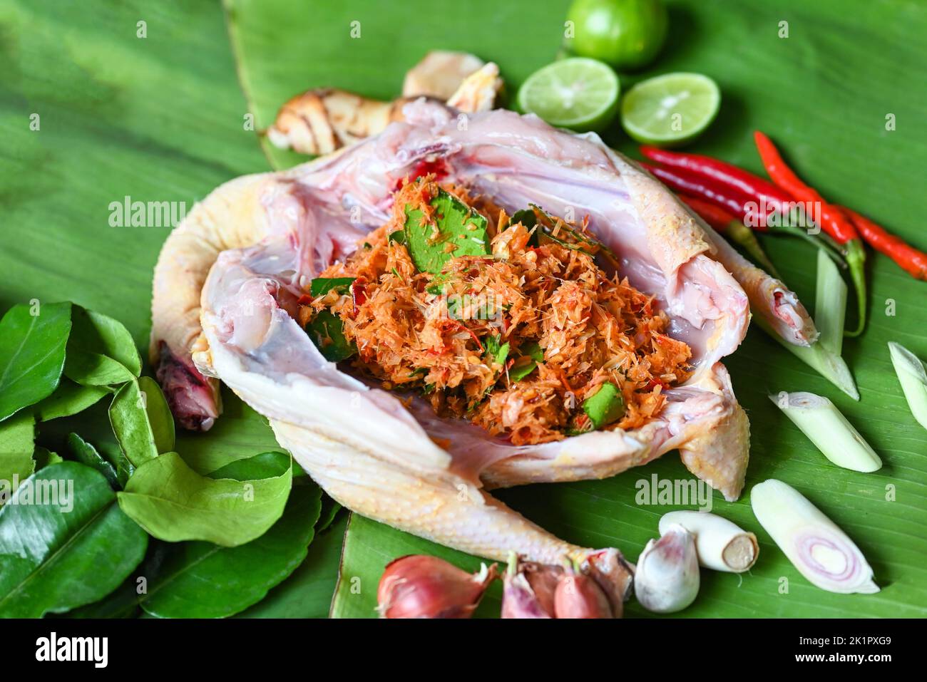 Thai food cooking with fresh chicken vegetables herbs and spices ingredients on banana leaf background, raw chicken with  lemon lime shallot garlic ga Stock Photo