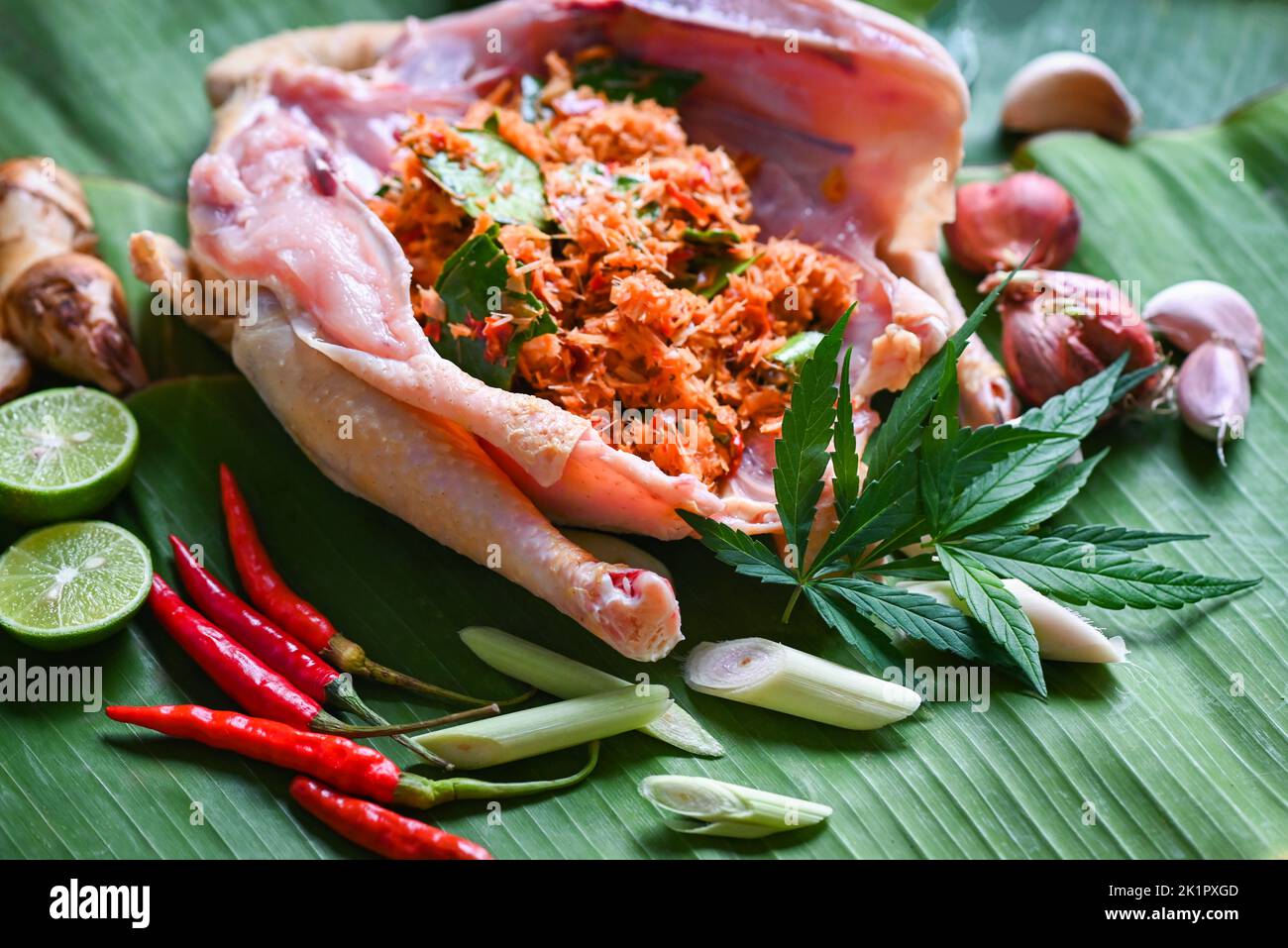 Cannabis food for cooking with fresh chicken cannabis leaf marijuana vegetables herbs and spices ingredients on banana leaf background, raw chicken he Stock Photo