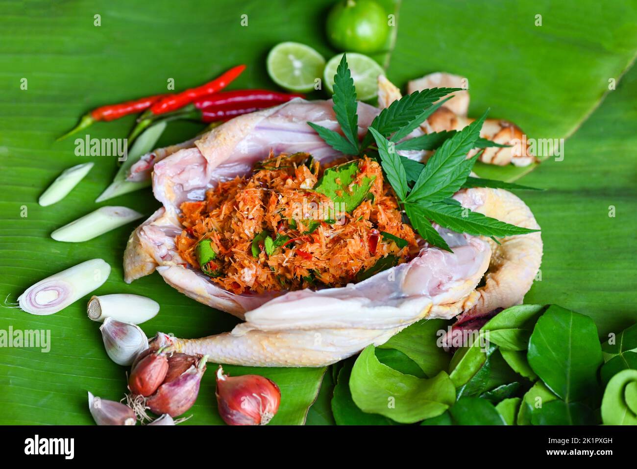 Cannabis food for cooking with fresh chicken cannabis leaf marijuana vegetables herbs and spices ingredients on banana leaf background, raw chicken he Stock Photo