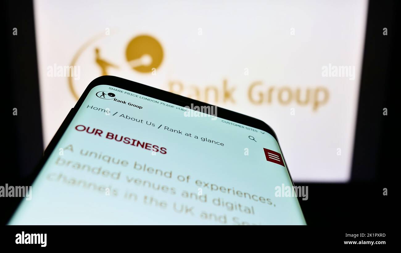 Mobile phone with website of British gambling company The Rank Group plc on screen in front of business logo. Focus on top-left of phone display. Stock Photo