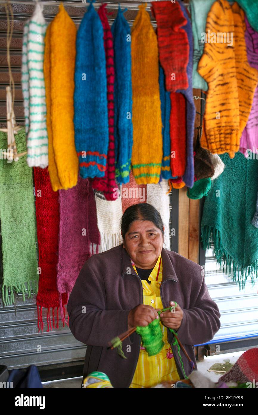 Chile, Quinchao a small island a short ferry trip from Chiloe island -Mapuche woman is knitting in while working in the market of Achao. Stock Photo