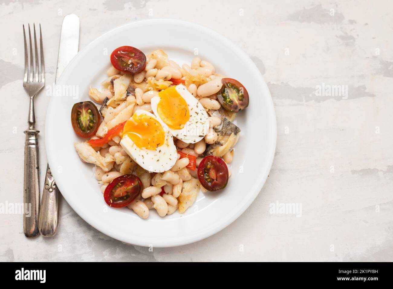 Salad with Fried cod fish and white beans on the plate. Stock Photo