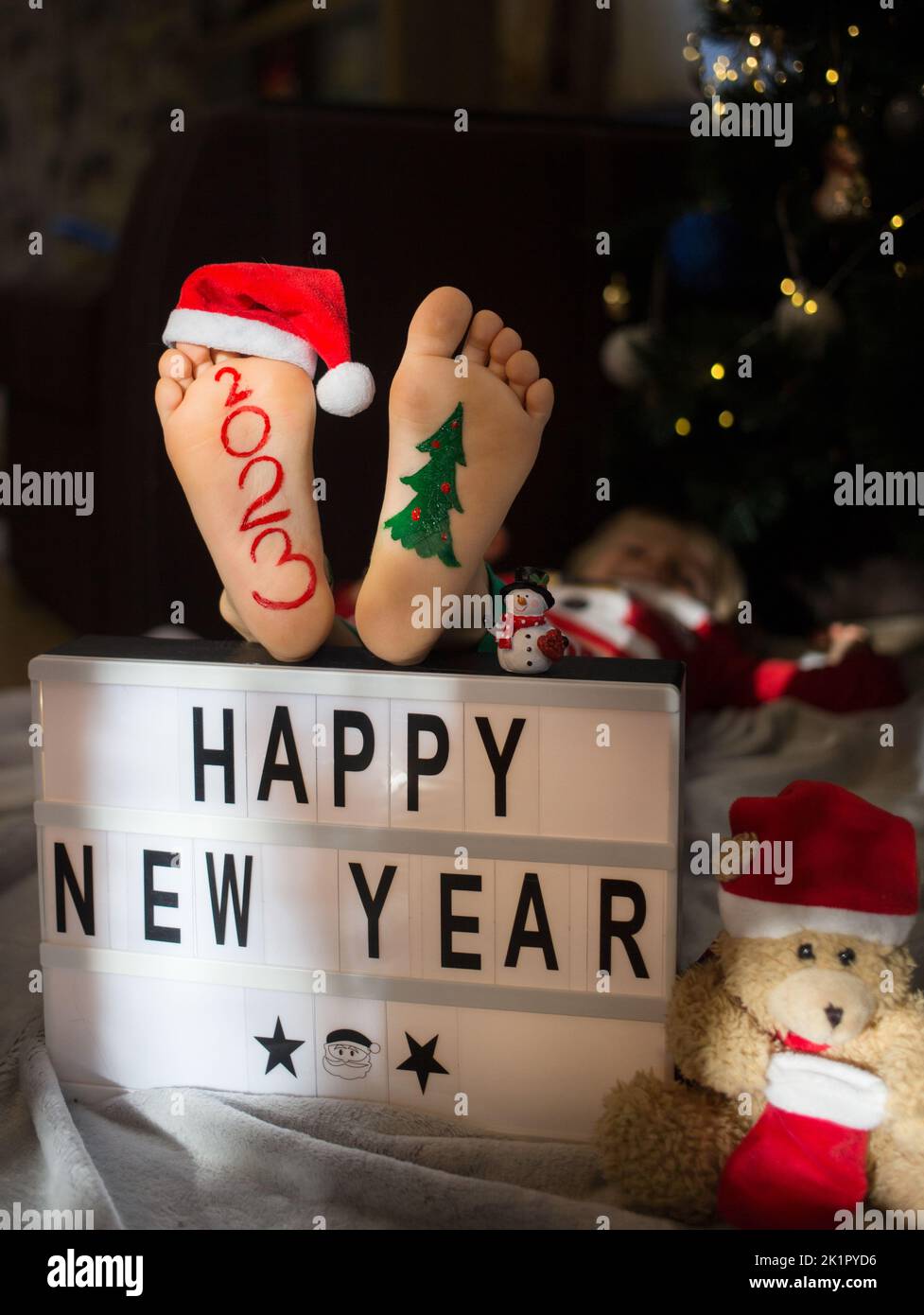 concept of preparing for Christmas. positive, pampering, humor. numbers 2023 are written on child's bare feet. inscription happy new year. festive coz Stock Photo